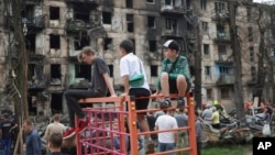 Діти дивляться, як розбирають завали на місці російського ракетного обстрілу, що пошкодив багатоповерховий житловий будинок у Кривому Розі, 13 червня 2023 р. Фото: AP/Andriy Dubchak