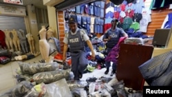 FILE - Police step over piles of suspected counterfeit clothing during a raid in Cape Town, South Africa, May 7, 2015. 