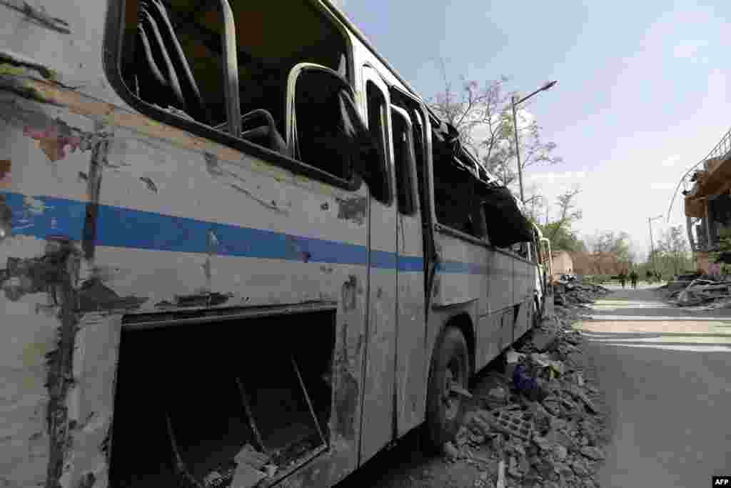 Một chiếc xe bus bị phá hủy gần đống đổ nát của Trung tâm Nghiên cứu Khoa học Syria, bị tấn công bởi các cuộc không kích của liên quân Mỹ, Anh và Pháp tại Barzeh, gần thủ đô Damascus, Syria, ngày 14 tháng 4 năm 2018.
