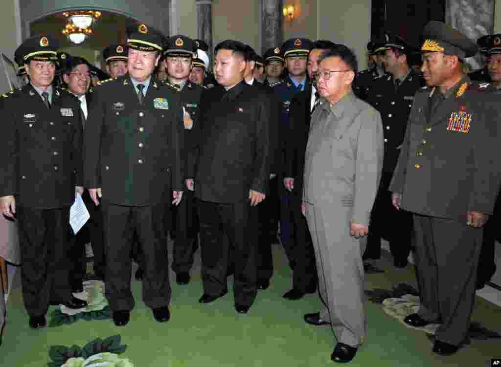 2010年10月25日,朝鲜领导人金正日和他的儿子金正恩在平壤接待郭伯雄上将率领的中国军事代表团,他们看着中方的礼物。郭伯雄此行是参加所谓的中国人民志愿军入朝参战60周年纪念活动。