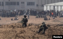 以色列士兵在加沙地带的以色列一边注视着巴勒斯坦抗议者。 （2018年5月14日）