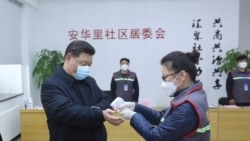 中国国家主席习近平戴着口罩视察北京安华里小区时一名防疫人员检测他的体温。（2020年2月10日）