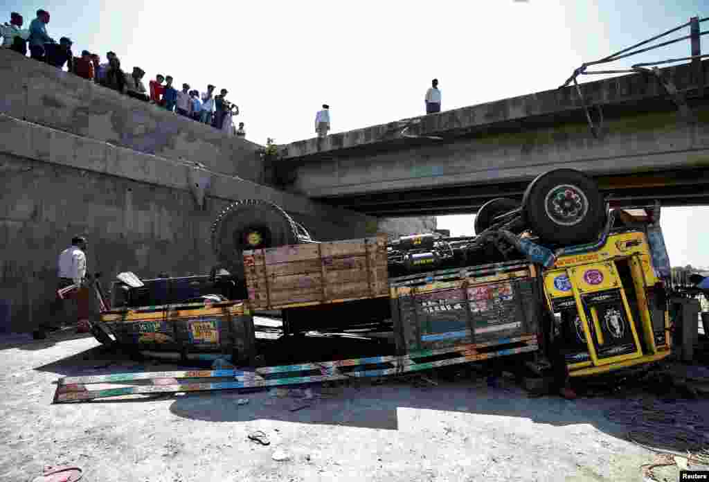 Police officers inspect the site of an accident after a truck carrying wedding party guests plunged into a dry riverbed, in Ranghola village in Bhavnagar district, in the western Indian state of Gujarat, India.