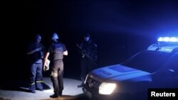 乌克兰城市克拉马托尔斯克市的警察宵禁开始后在夜间巡逻时检查一名行人的证件（2022年8月5日）