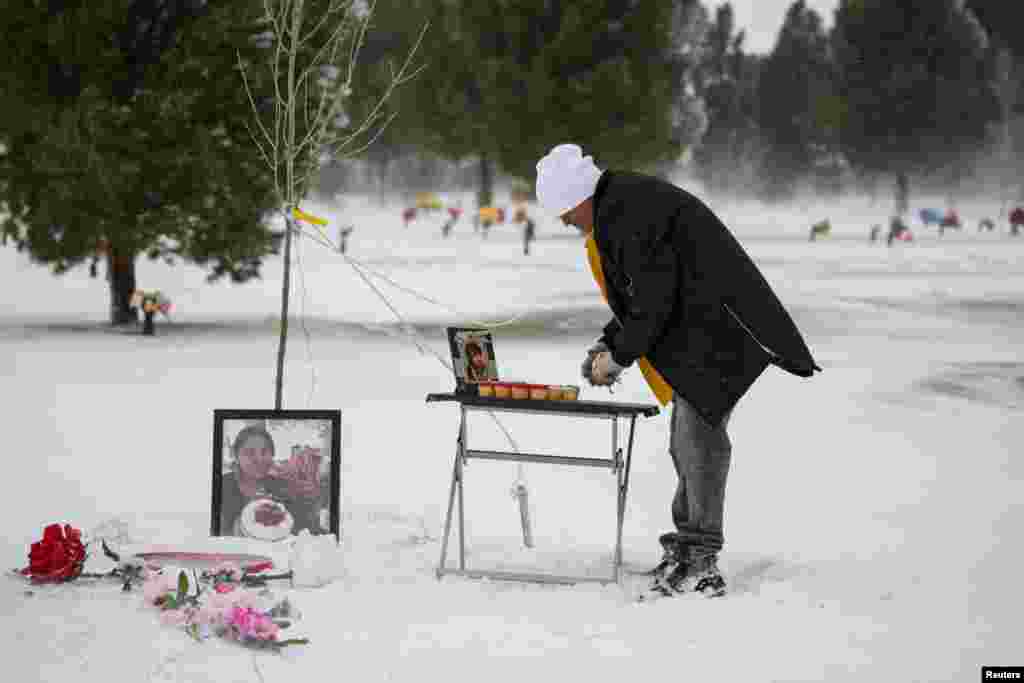 Antonio Cervantes brings gifts to the grave of his wife Gabriela, who died of the coronavirus disease (COVID-19), for Valentine's Day, at a cemetery in Santa Teresa, New Mexico, Feb. 14, 2021.