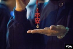 台北第二殡仪馆内的慈济义工在现场分发“平安”挂饰。（美国之音记者方正拍摄）