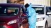 A medical technician performs a nasal swab test on a motorist at a COVID-19 testing site near All City Stadium, Dec. 30, 2021, in Denver. With the rapid spread of the omicron variant paired with the Christmas holiday, testing sites have been strained to m