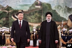 2023 年 2 月 14 日，在北京人民大会堂举行的欢迎仪式上，来访的伊朗总统易卜拉欣·莱希（Ebrahim Raisi）（右）在检阅仪仗队后与中国国家主席习近平同行。