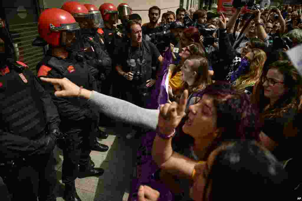 People shout slogans next to a line a policemen during a women's rights protest in front of the Regional Court in Pamplona, northern Spain