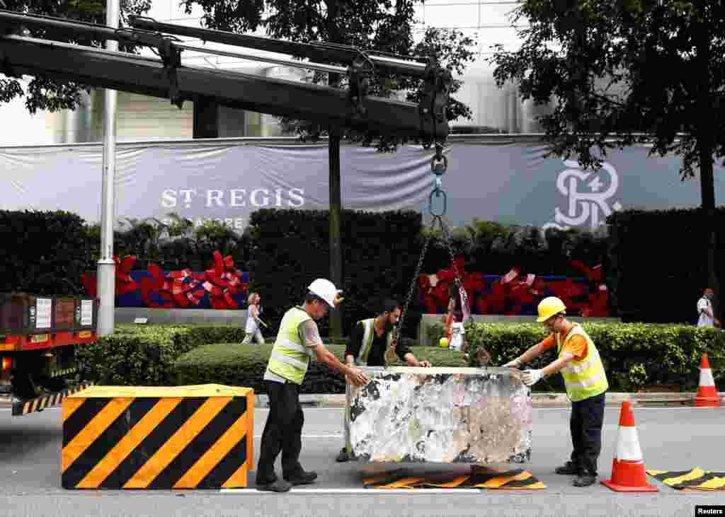 工人在新加坡瑞吉酒店外设置路障(2018年6月9日)。美朝首脑峰会即将举行之际,新加坡当局加强保安,宣布两个峰会相关地点为“特别事件专区”,一个是圣淘沙岛,另一个在唐林区。当局在唐林区一些道路上设置了混凝土路障。那个区域靠近美国驻新加坡大使馆以及好几个饭店,其中包括美国代表团下榻的香格里拉大酒店。