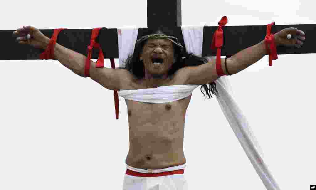 Ruben Enaje grimaces after gets nailed to the cross for the 32nd year in a row during a reenactment of Jesus Christ's sufferings as part of Good Friday rituals in the village of San Pedro Cutud, Pampanga province, northern Philippines.