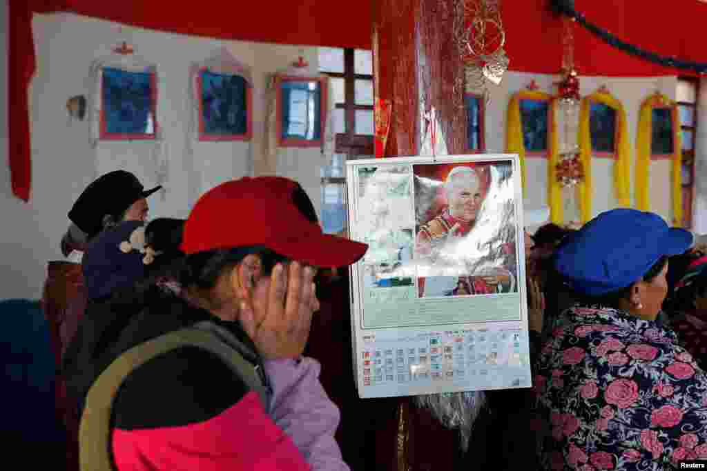2018年12月24日圣诞节前夕,中国云南省迪庆藏族自治州的西藏天主教徒做弥撒,柱子上挂着带有教宗约翰·保罗二世头像的挂历。