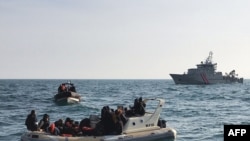 FILE - A handout image from France's Societe Nationale de Sauvetage en Mer on Feb. 18, 2019, shows British rescuers (front) helping some 20 migrants on a semirigid boat trying make their way from France across the English Channel.