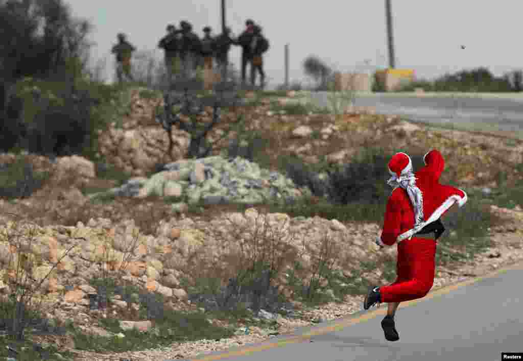 A Palestinian demonstrator dressed as Santa Claus hurls stones towards Israeli troops during clashes at a protest against U.S. President Donald Trump's decision to recognize Jerusalem as the capital of Israel, near the West Bank city of Ramallah.