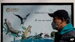 2020年3月11日，中国北京，一名戴着口罩的男子经过一张宣传保护野生动物的海报。