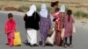 FILE - Women and children from the minority Yazidi sect, fleeing the violence in the Iraqi town of Sinjar, walk to a refugee camp after they re-entered Iraq from Syria at the Iraqi-Syrian border crossing in Fishkhabour, Dohuk province, Aug. 14, 2014.