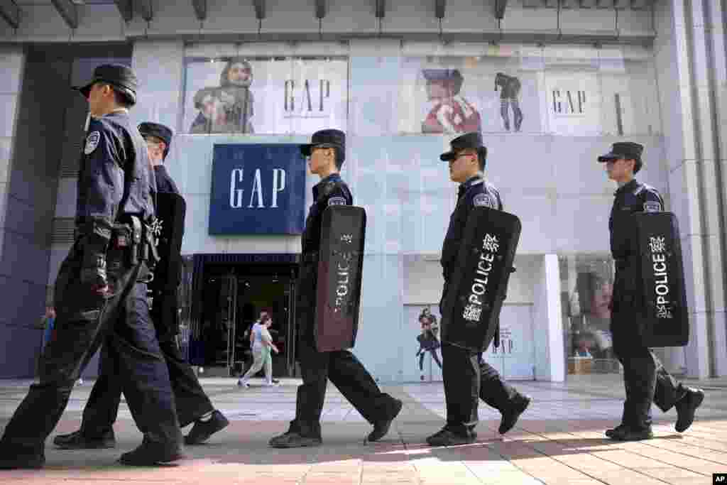2018年9月25日,中国警察在北京一个购物区巡逻,路过美国服装零售商Gap的商店。