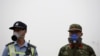 A paramilitary policeman and a policeman, both wearing masks, stand guard at a location within a 3-km (2-mile) exclusion zone from last week's explosion site in Binhai new district in Tianjin, China, Aug. 18, 2015. 