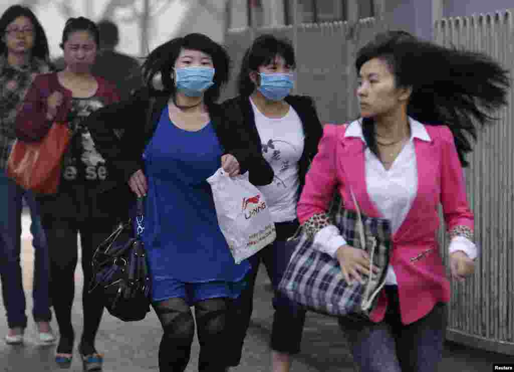 Phụ nữ đeo mặt nạ chạy băng qua một đường phố ở Bắc Kinh, ngày 0 tháng 5, 2013.