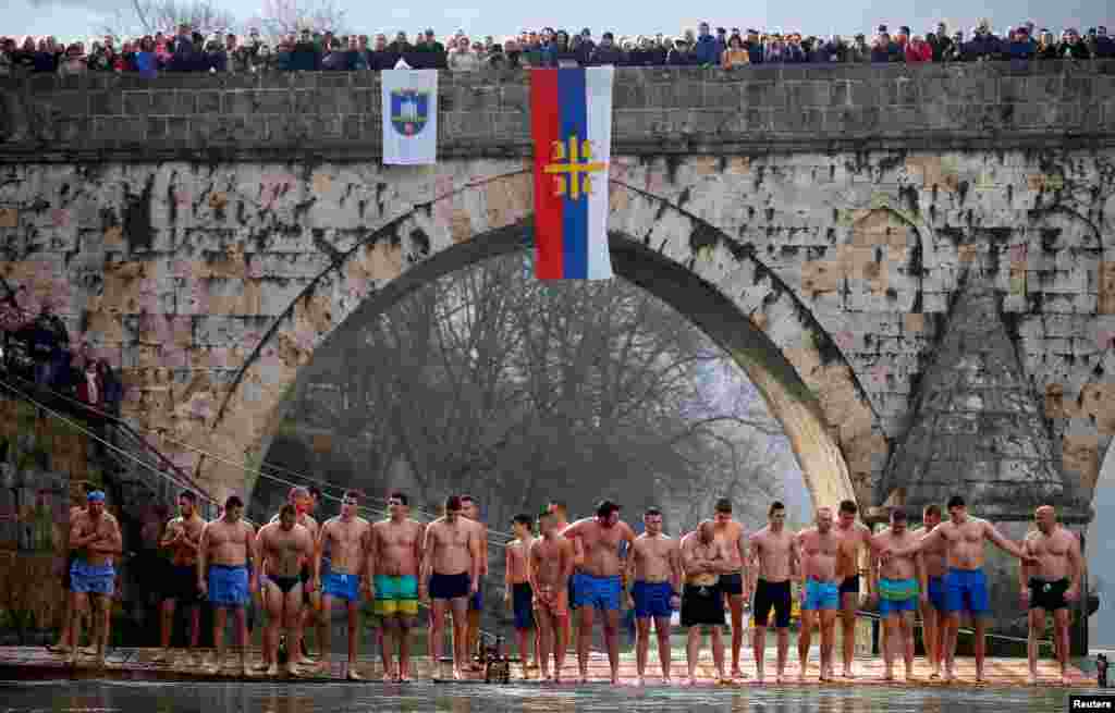 Men wait before a swim to try retrieve a cross from the water during Epiphany Day celebrations in Visegrad, Bosnia and Herzegovina.