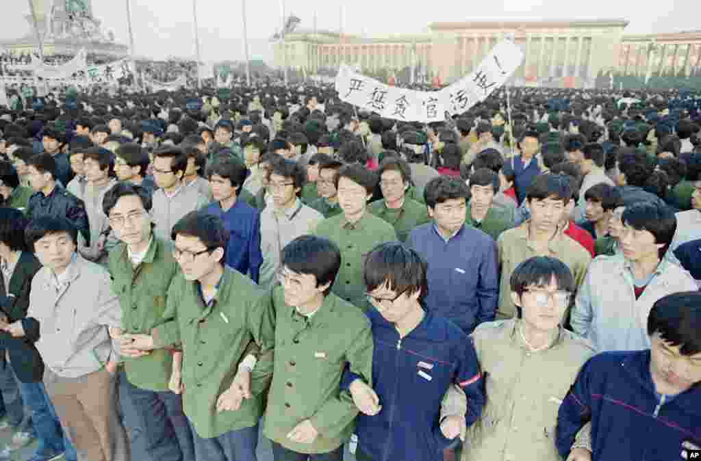 黎明时，学生们在北京天安门广场上手臂挽手臂，团结在一起。此次活动是为了悼念前中国共产党总书记胡耀邦（1989年4月22日）