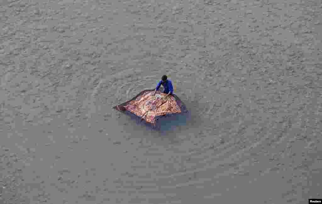 A man washes a blanket on the banks of the river Tawi in Jammu, India.