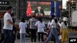 北京街头的行人观看电子屏幕上中国国家主席习近平通过视频在世卫大会视频开幕式上致辞。（2020年5月18日）