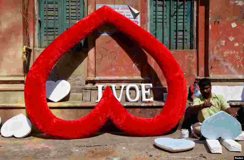 An artisan paints hearts made of polystyrene at a road side workshop ahead of Valentine's Day, in Kolkata, India.