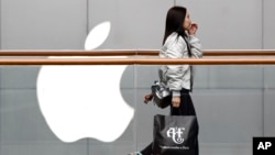 一位女士手提美国品牌Abercrombie＆Fitch的购物袋，经过在北京广受欢迎的苹果商店。（2019年2月26日）