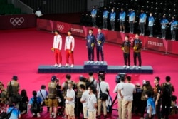 东京奥运会羽毛球男双颁奖台上，台湾选手李洋及王齐麟获金牌，中国选手李俊慧与刘雨辰获银牌，马来西亚选手获铜牌。（2021年7月31日）