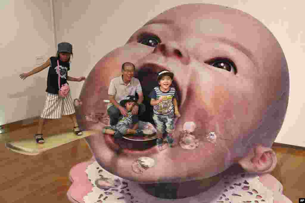 在东京附近的川崎举行的三维技巧展览中，参观者和日本艺术家 Masashi Hattori 创造的一个3D图像合影。（2011年8月5日）