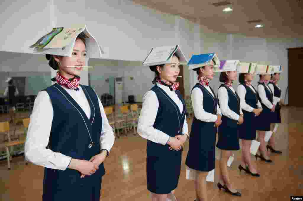 河北石家庄的空乘培训学校,想当空姐的学员们训练站立姿势和仪态,头上顶着书本以保持抬头挺胸,嘴里含着筷子以保持微笑,膝盖夹着纸张以保持并拢(2017年5月4日)