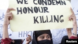 FILE - A Pakistani woman holds a placard during a protest against honor killings in Multan, Oct. 27, 2004. 