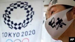 一名日本女子站在东京奥运会标识旁。（2021年4月10日）