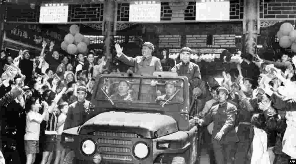 1967年5月1日毛泽东(1893-1976)和林彪(1907-1971)在敞篷吉普车上向在北京天安门广场一带庆祝五一节的群众挥手致意。坐在毛泽东前面的人似乎是汪东兴。