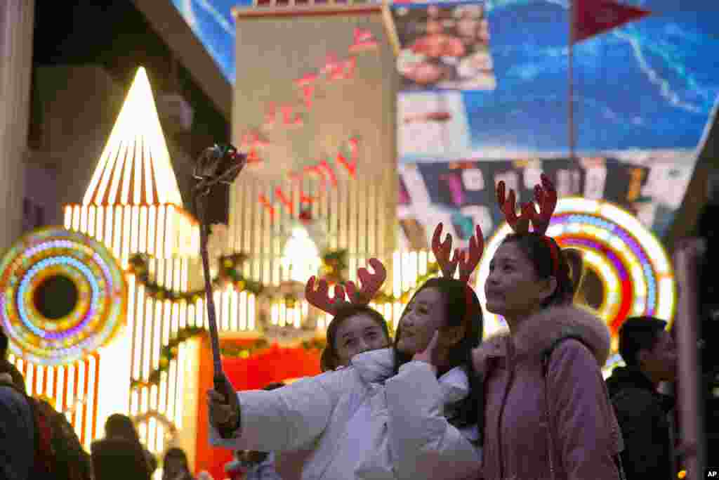 2017年12月24日,北京圣诞节前夕,三位中国女孩在一家购物中心自拍。