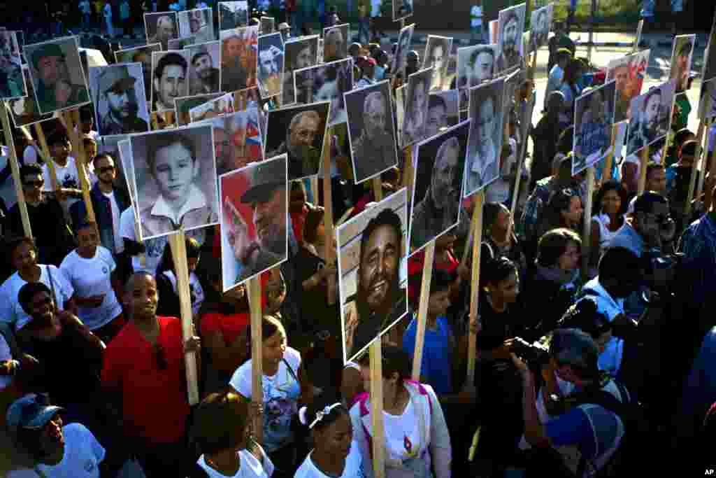 People hold photos of Cuba's late leader Fidel Castro in a march to commemorate one year since Castro was buried, in Santiago.