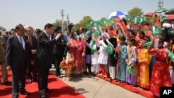 FILE - Chinese President Xi Jinping waves to children with Pakistan's Present Mamnoon Hussain, left, upon his arrival at Nur Khan airbase in Islamabad, Pakistan, April 20, 2015.