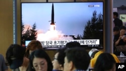 人们在韩国首尔一个地铁站的屏幕前看朝鲜导弹试射的新闻，2019年7月25日