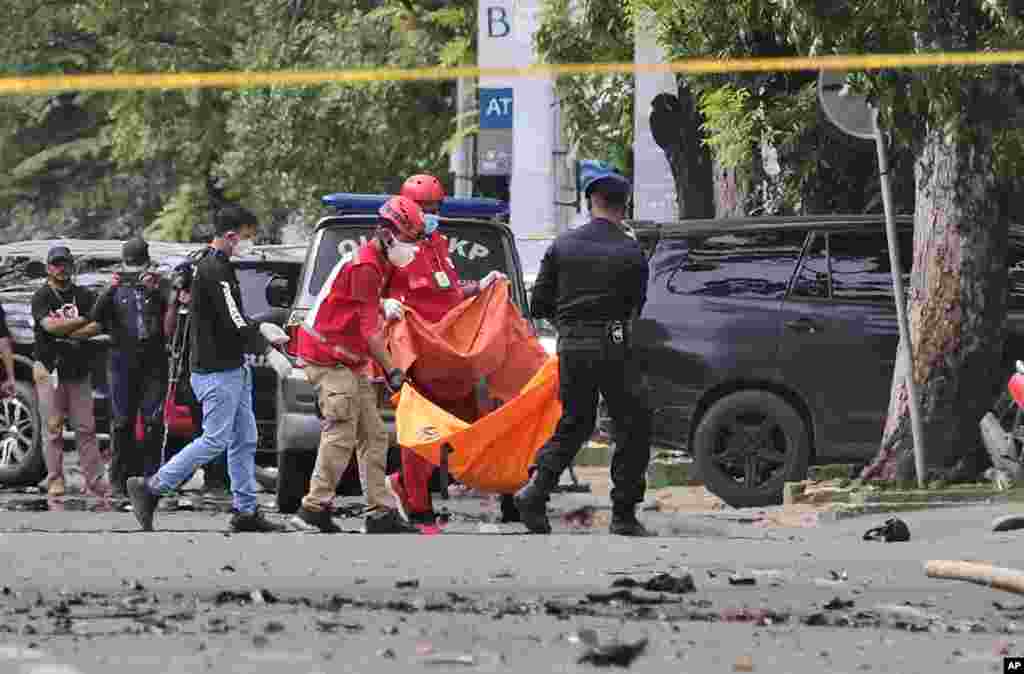 Police officer and rescue workers carry a body bag containing what is believed to be human remains outside a church where an explosion went off in Makassar, South Sulawesi, Indonesia. A suicide bomber blew himself up outside a packed Roman Catholic cathedral during a Palm Sunday Mass, wounding a number of people, police said. 