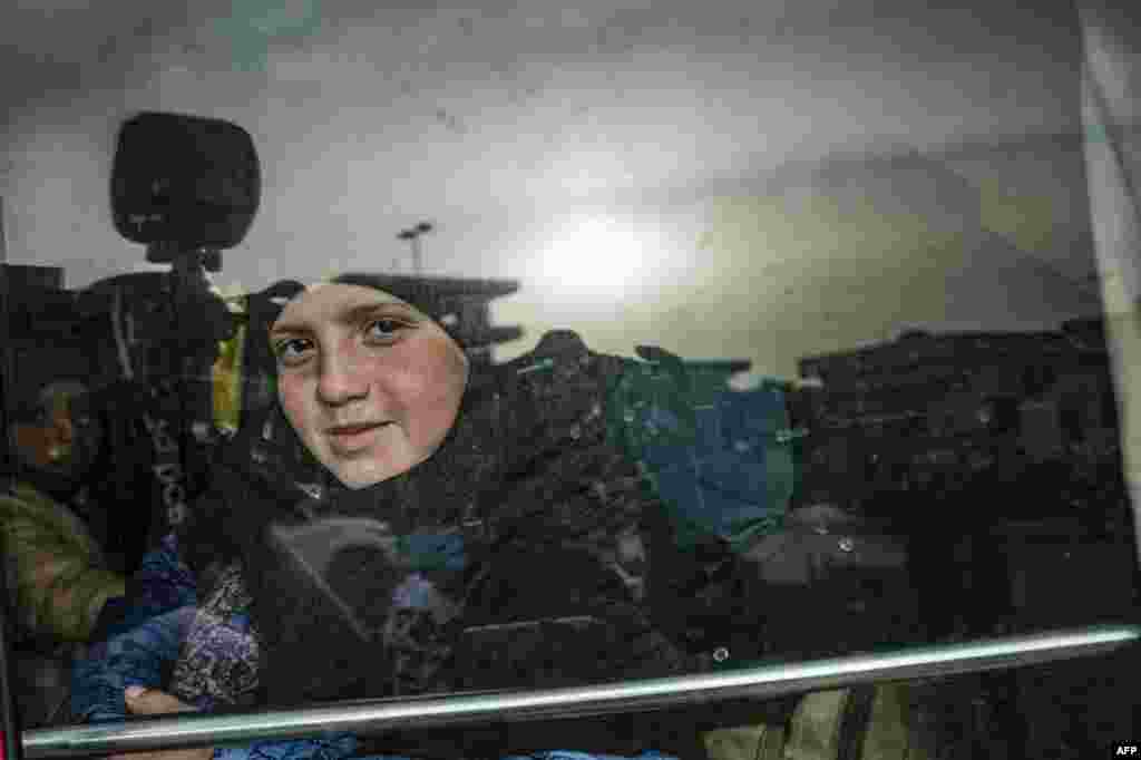 A child sits in a bus during the handover of orphaned children, whose parents were suspected of belonging to the Islamic State group, to a Russian delegation by Syrian Kurdish officials, at the headquarters of the department for foreign affairs of the semi-autonomous Kurdish administration in Syria's northeastern city of Qamishli, April 18, 2021.