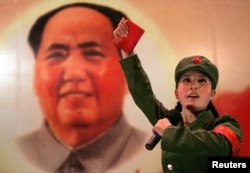 打扮成红卫兵的少女手持《毛主席语录》，在北京一家名为“红色经典”的餐厅中的毛主席像前表演（2006年4月7日）