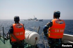 越南海岸警卫队成员在离越南海岸大约210公里处的南中国海海域观察一艘中国海警船。（2014年5月15日）
