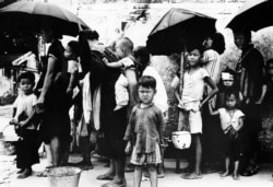 1962年5月拍摄的照片显示，逃离中国大饥荒的难民在香港排队领取食物。
