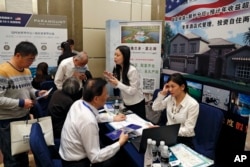 在妮可·库什纳（Nicole Kushner Meyer现身北京的一场投资移民项目（EB-5）推介会的一天之后，在投资美国展览中，在EB-5签证项目摊位上，中国人询问信息（2017年5月7日）