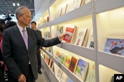 中国驻美大使崔天凯在纽约书展的中国摊位拿起一本论述中共在中国为何成功、如何成功的书（2015年5月27日）