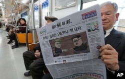 一位乘客在韩国首尔的地铁列车上阅读报道朝鲜领导人金正恩与美国总统唐纳德·川普计划举行高峰会议的报纸。（2018年3月10日）