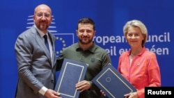 Президент Європейської ради Шарль Мішель, президент України Володимир Зеленський та президентка Європейської комісії Урсула фон дер Ляєн беруть участь у церемонії підписання угоди між Україною та ЄС про безпеку в Брюсселі, 27 червня 2024 року. OLIVIER HOSLET/REUTERS