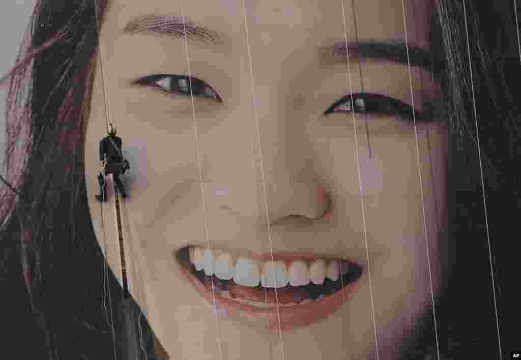 A worker hangs on a rope to adjust an image on a building in Seoul, South Korea.