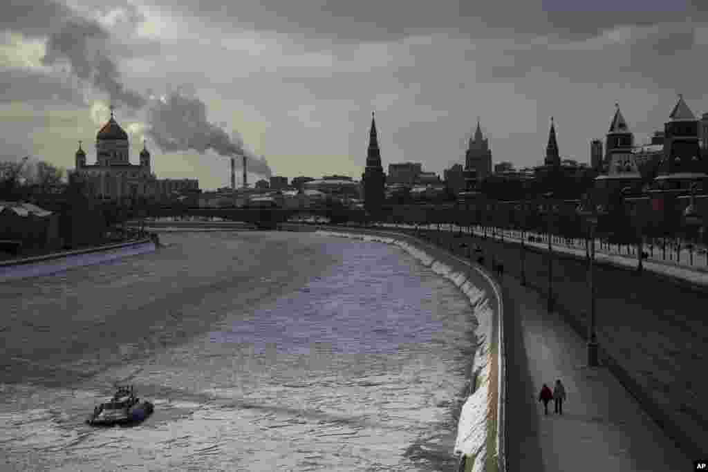 A couple walk along the frozen Moskva River, next to the Kremlin Wall, and the Christ the Saviour Cathedral, left, in Moscow, Russia.